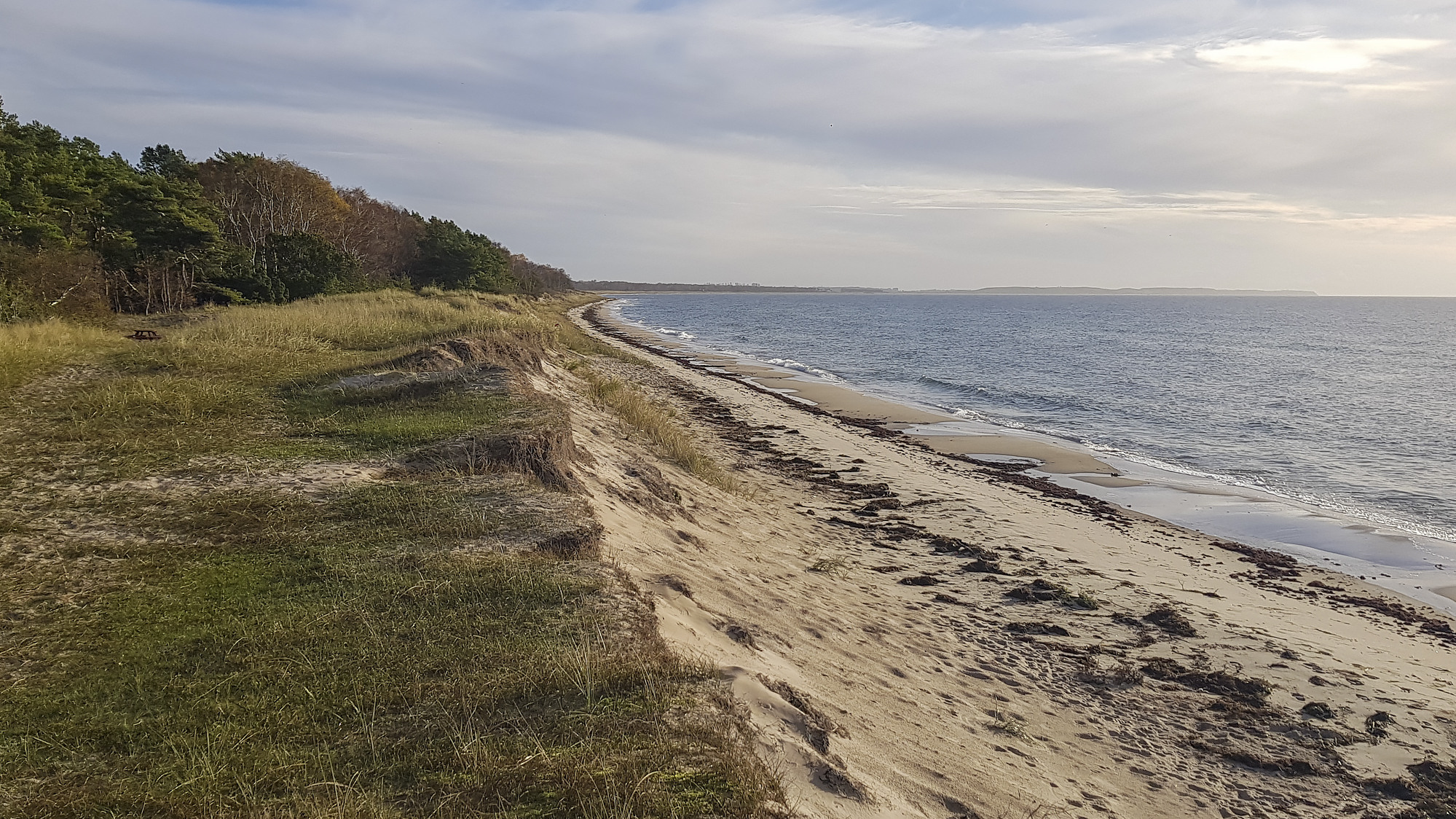 En sandstrand intill havet under en molnig himmel