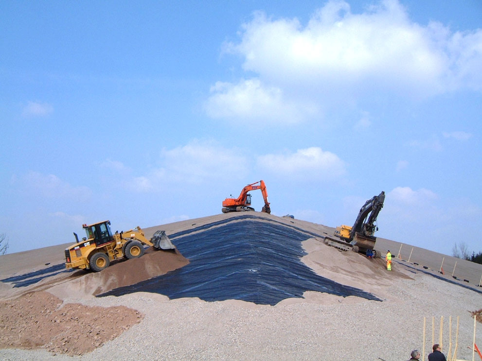 En grupp byggnadsarbetare står på toppen av en kulle