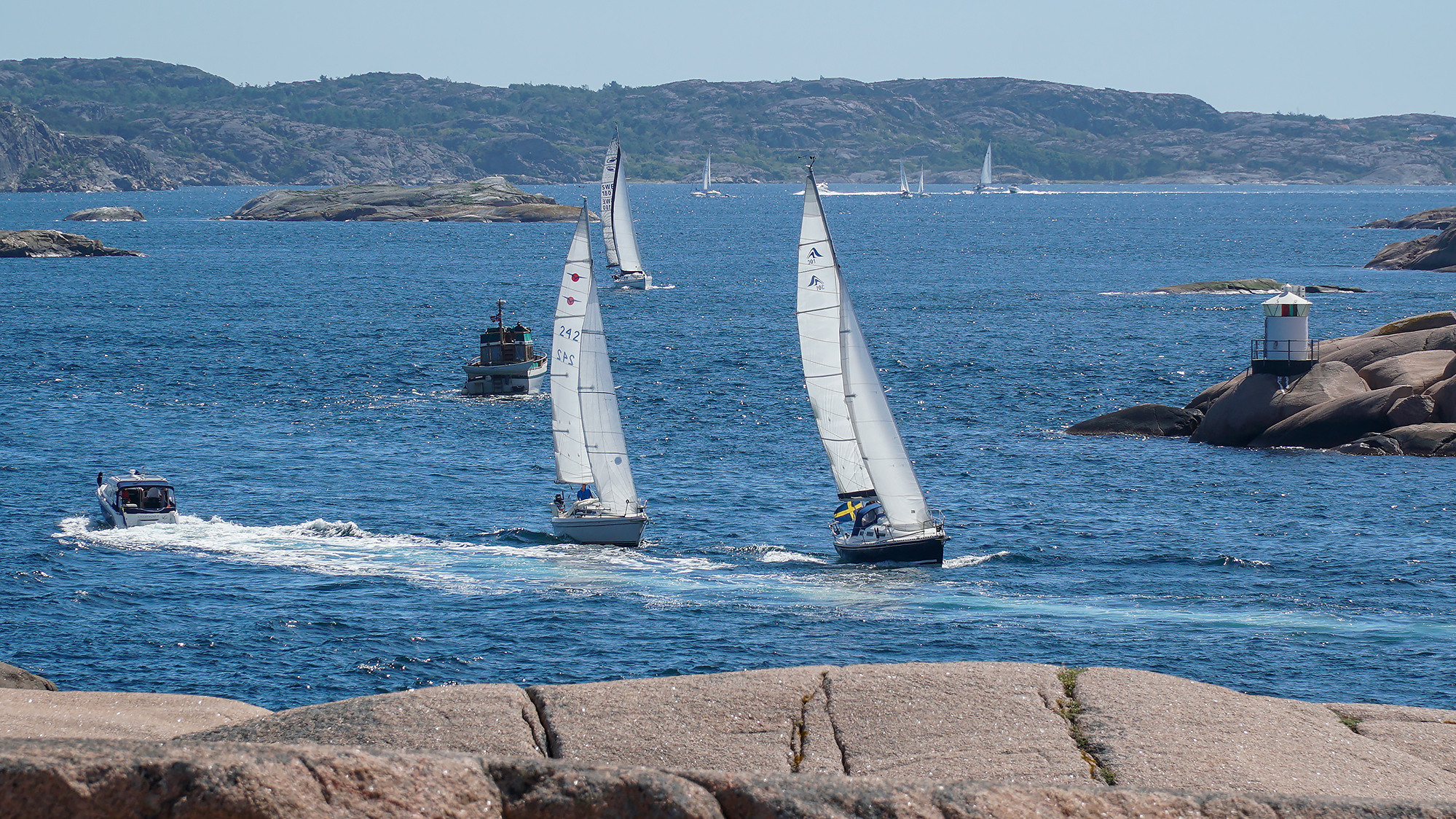 En grupp segelbåtar som seglar på ett vattendrag.