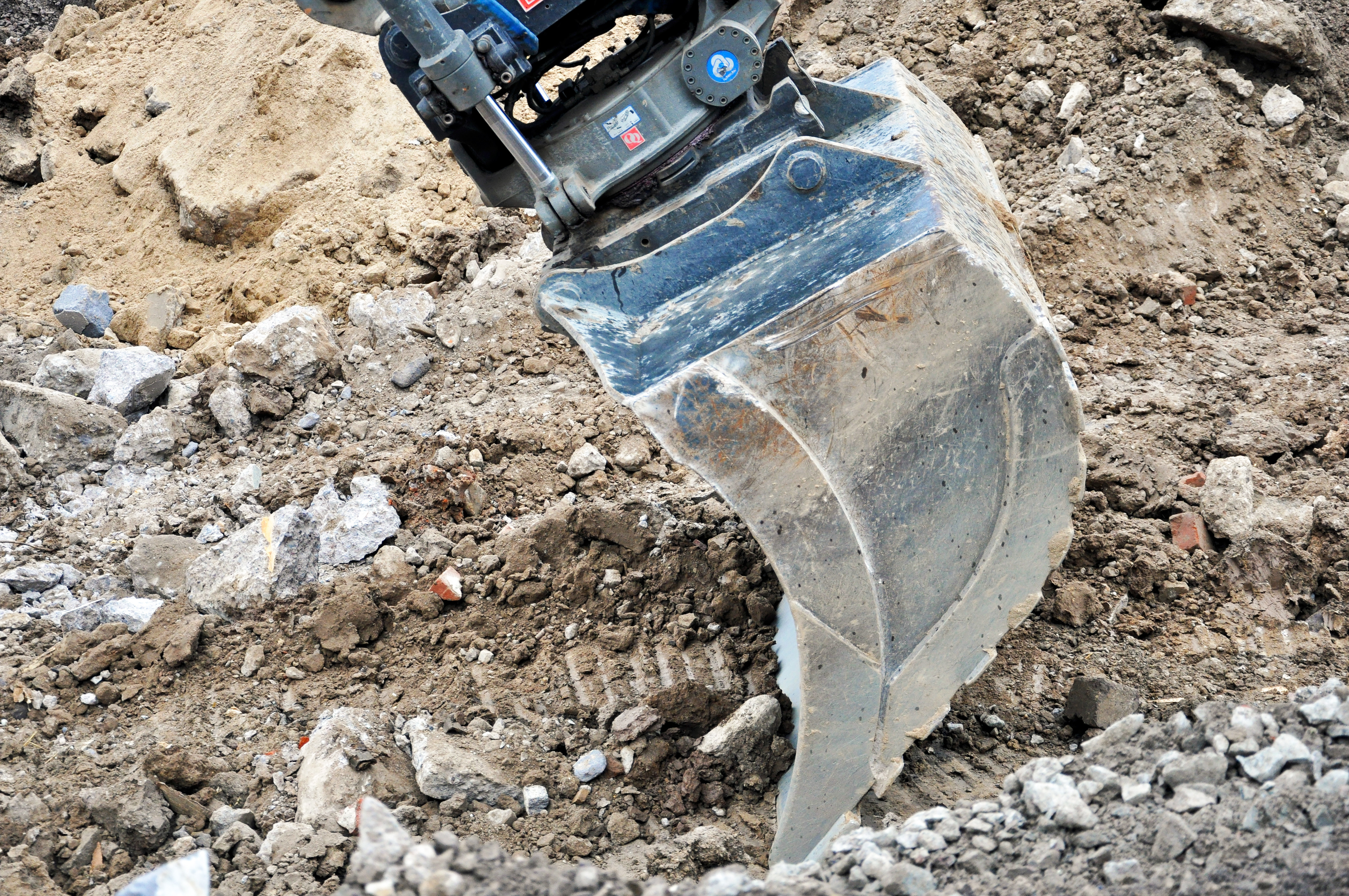 Närbild på en skopa som gräver sig igenom en hög med jord