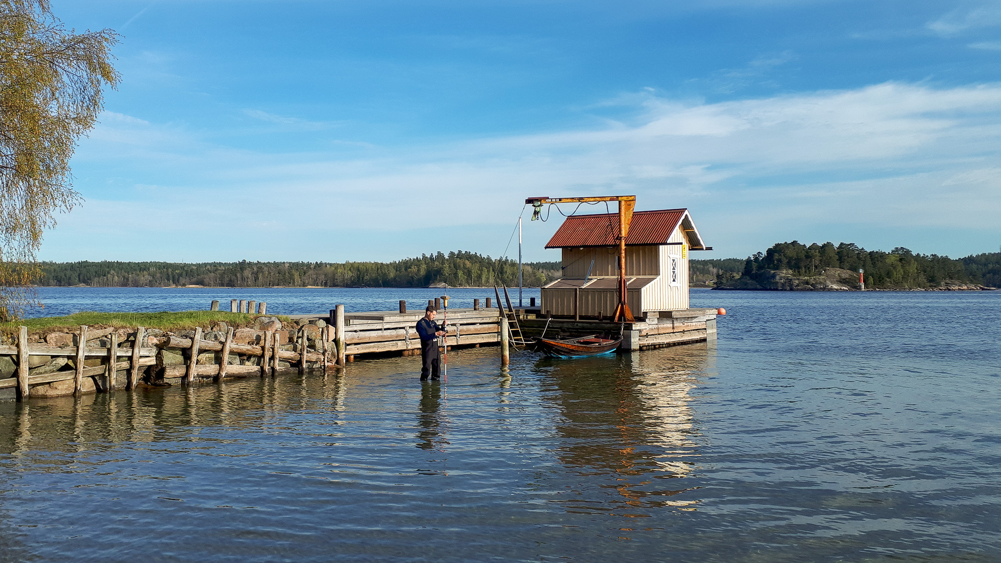 En man som står i vattnet bredvid en brygga.