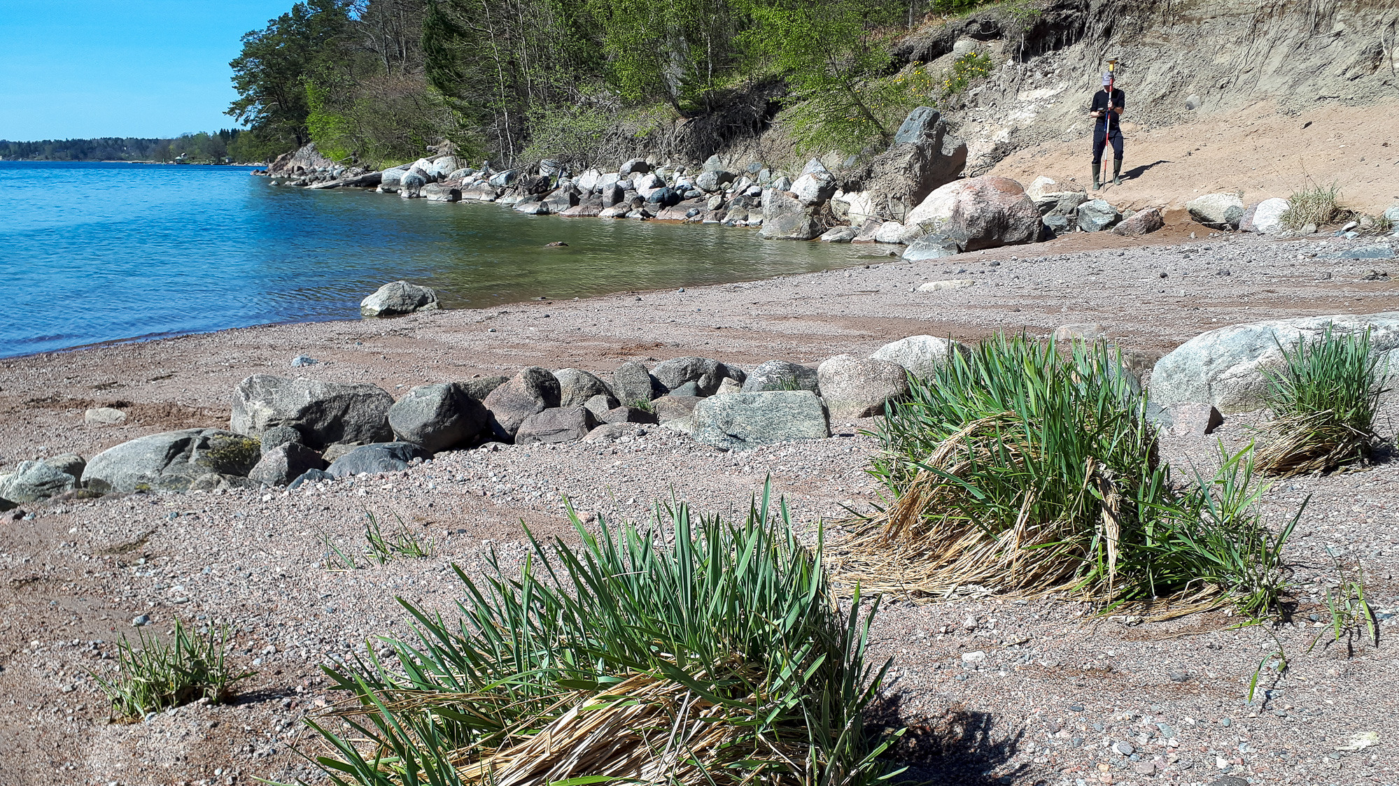 En man som står på en strand intill ett vattendrag.