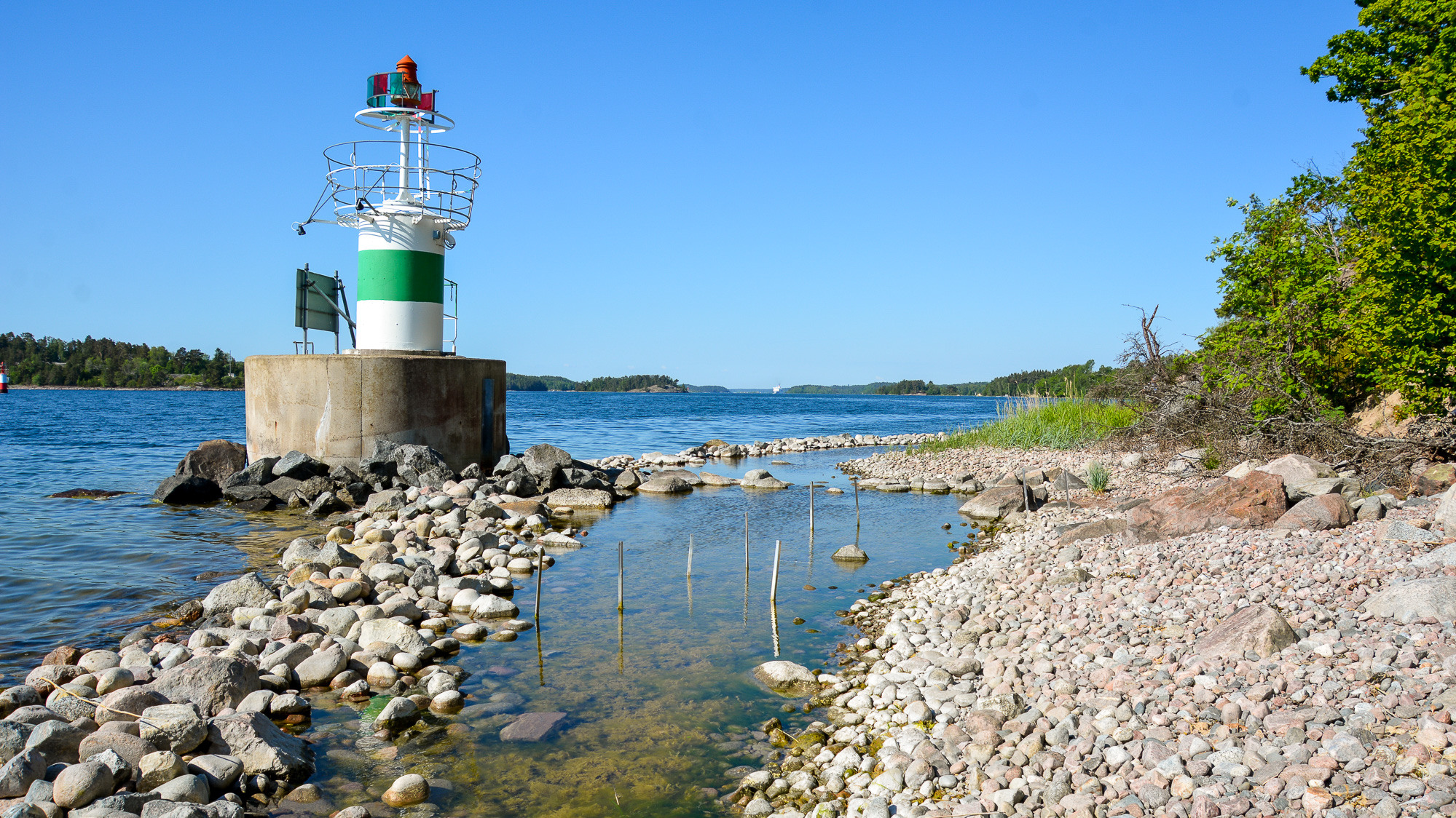 Ett ljust hus som sitter på toppen av en klippig strand.