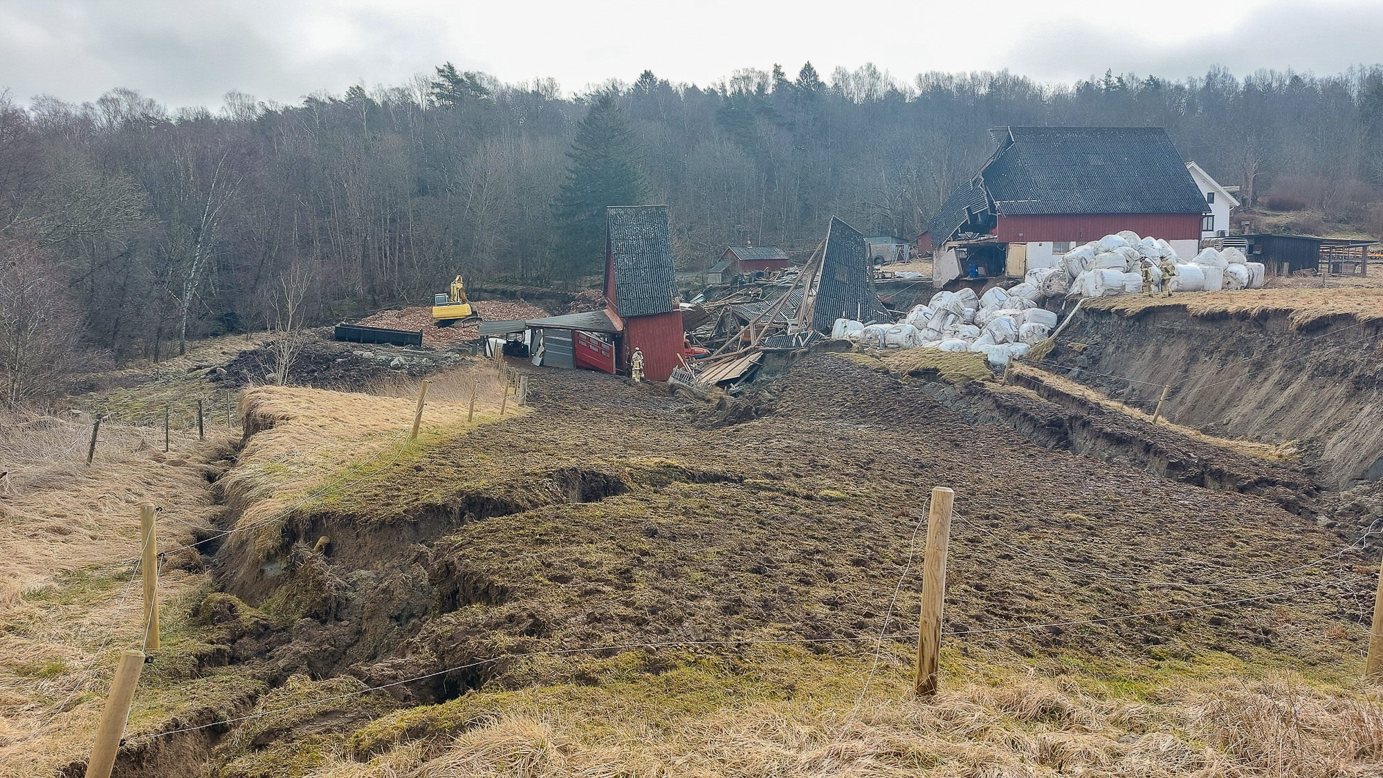 En jordkulle med en lada och en röd byggnad i bakgrunden.